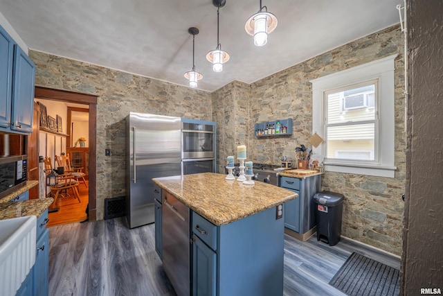 405 Washington St, Pekin, IL 61554 - kitchen with blue cabinetry, appliances with stainless steel finishes, dark wood-type flooring, a center island, and light stone counters
