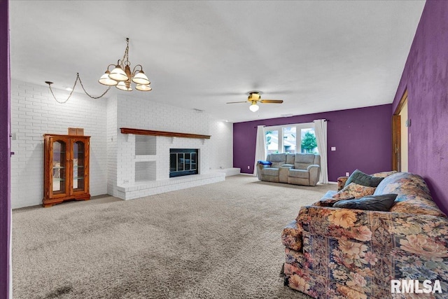 carpeted living room featuring ceiling fan, a chandelier, and a fireplace