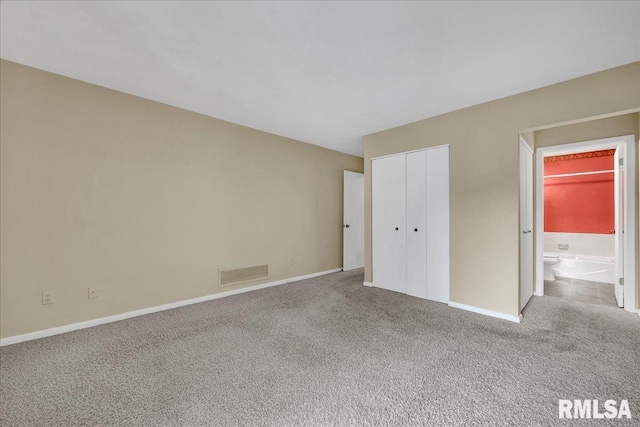 unfurnished bedroom with carpet, baseboards, ensuite bath, and a closet