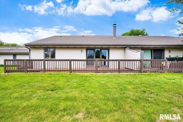 rear view of property featuring a lawn and roof with shingles