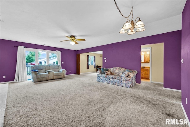 carpeted living area with baseboards, ceiling fan, and a chandelier