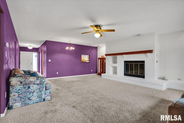 unfurnished living room featuring carpet flooring, ceiling fan, a brick fireplace, a chandelier, and brick wall