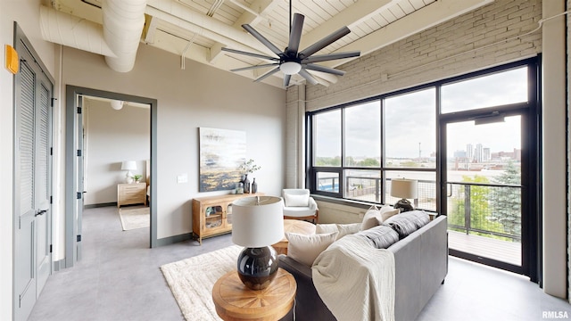 1001 SW Adams St Unit 304, Peoria, IL 61602 - living area featuring wooden ceiling with exposed beams, ceiling fan, finished concrete floors, baseboards, and a towering ceiling