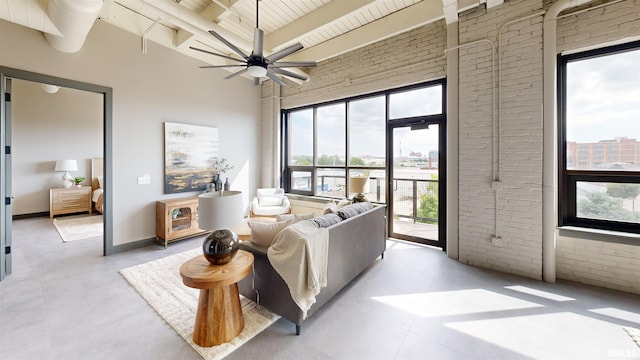 1001 SW Adams St Unit 304, Peoria, IL 61602 - living area featuring brick wall, plenty of natural light, a ceiling fan, a high ceiling, and wooden ceiling with exposed beams