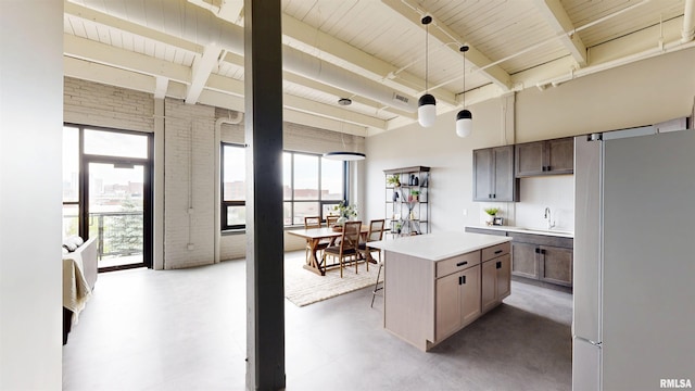 1001 SW Adams St Unit 304, Peoria, IL 61602 - kitchen featuring freestanding refrigerator, a sink, beamed ceiling, light countertops, and finished concrete flooring