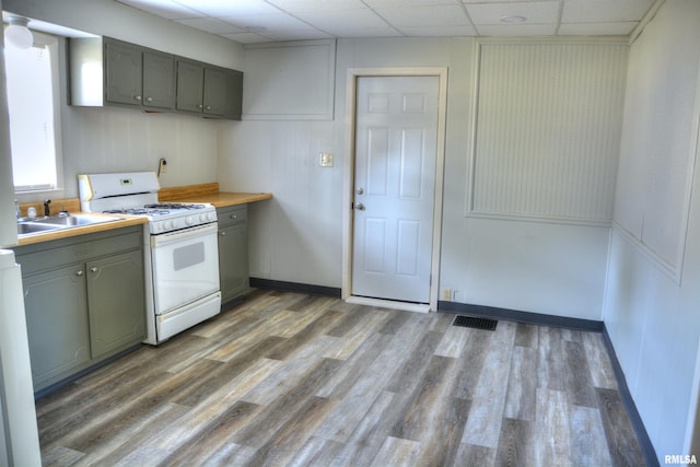 309 S Dudley St, Macomb, IL 61455 - kitchen featuring white gas range, a sink, gray cabinets, a paneled ceiling, and wood finished floors