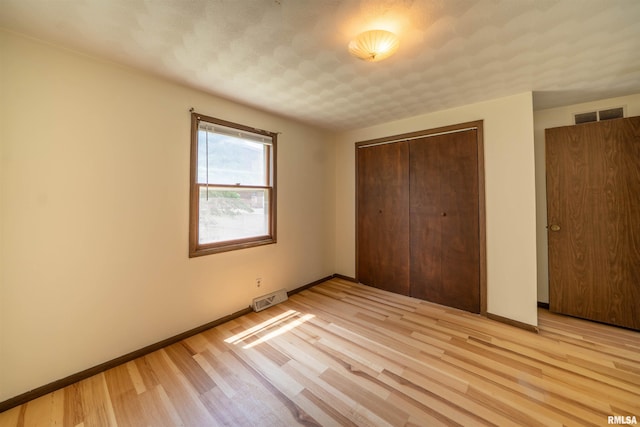 2706 W Millbrook Ct, Peoria, IL 61615 - unfurnished bedroom with light wood-type flooring, a closet, and baseboards