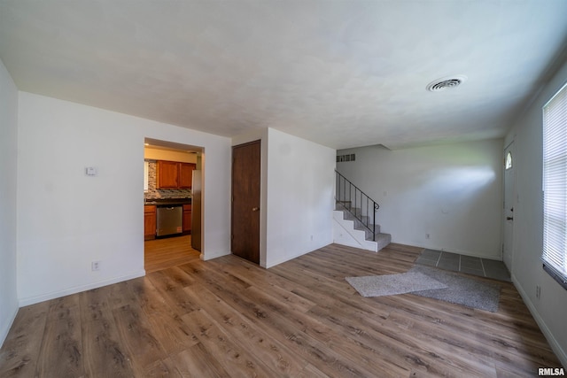 2706 W Millbrook Ct, Peoria, IL 61615 - unfurnished living room with light wood-type flooring, stairs, and baseboards