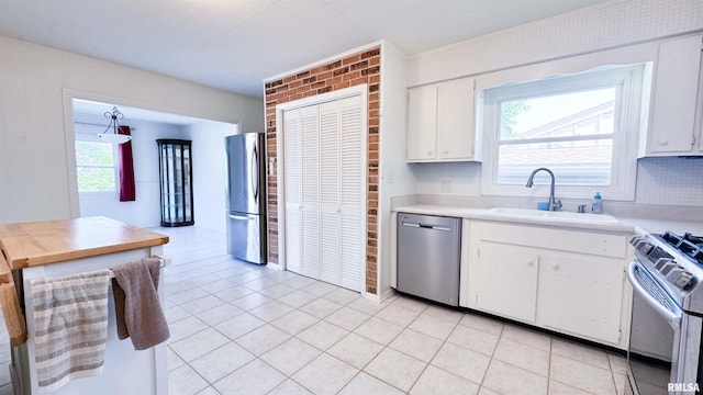 7409 N Piccadilly Pl, Peoria, IL 61614 - kitchen with appliances with stainless steel finishes, light countertops, white cabinets, light tile patterned floors, and brick wall
