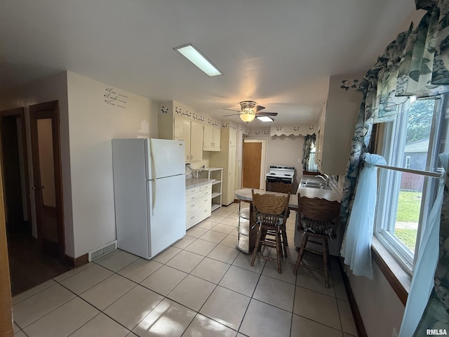 130 E Maple St, Roseville, IL 61473 - kitchen featuring white appliances, a sink, light tile patterned floors, light countertops, and white cabinetry