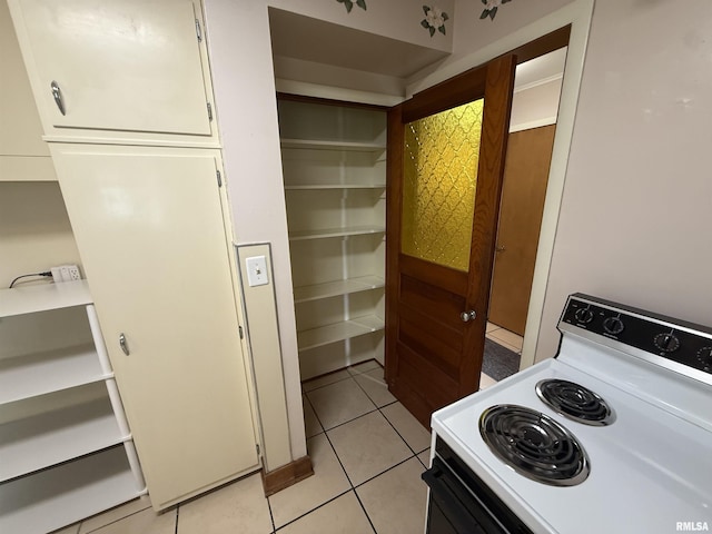 130 E Maple St, Roseville, IL 61473 - kitchen featuring white electric range oven, light tile patterned floors, white cabinets, and light countertops