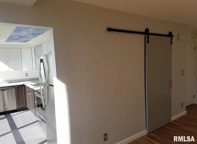 125 SW Jefferson Ave Unit W4S, Peoria, IL 61602 - kitchen featuring a barn door, baseboards, light countertops, light wood finished floors, and stainless steel appliances