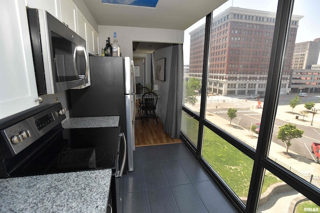 125 SW Jefferson Ave Unit W4S, Peoria, IL 61602 - kitchen with appliances with stainless steel finishes, white cabinetry, dark tile patterned flooring, and a view of city