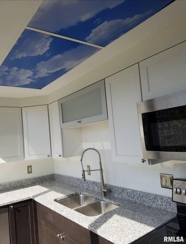 125 SW Jefferson Ave Unit W4S, Peoria, IL 61602 - kitchen featuring appliances with stainless steel finishes, a sink, dark brown cabinets, white cabinets, and light stone counters
