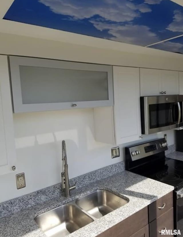 125 SW Jefferson Ave Unit W4S, Peoria, IL 61602 - kitchen with stainless steel appliances, a sink, white cabinets, and light stone counters