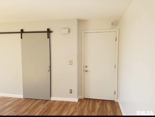 125 SW Jefferson Ave Unit W4S, Peoria, IL 61602 - unfurnished bedroom featuring light wood-style flooring, baseboards, and a barn door