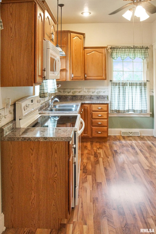 418 W Clinton St, Toulon, IL 61483 - kitchen with white appliances, a sink, ceiling fan, wood finished floors, and brown cabinetry