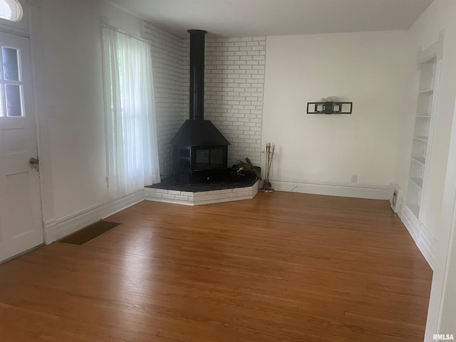 623 S Randolph St, Macomb, IL 61455 - unfurnished living room featuring wood finished floors, built in features, a wood stove, and baseboards