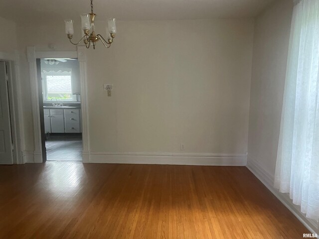 623 S Randolph St, Macomb, IL 61455 - unfurnished dining area with a chandelier, wood finished floors, a sink, and baseboards