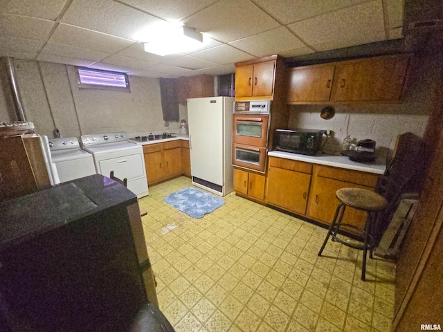 3303 W Chartwell Rd, Peoria, IL 61614 - kitchen with washing machine and clothes dryer, freestanding refrigerator, light floors, black microwave, and light countertops