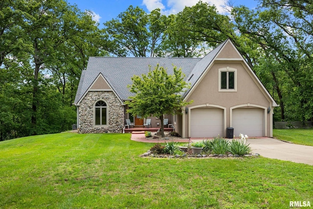 131 Lakeside Pl, Dahinda, IL 61428 - view of front of house featuring stone siding, a front lawn, concrete driveway, roof with shingles, and stucco siding