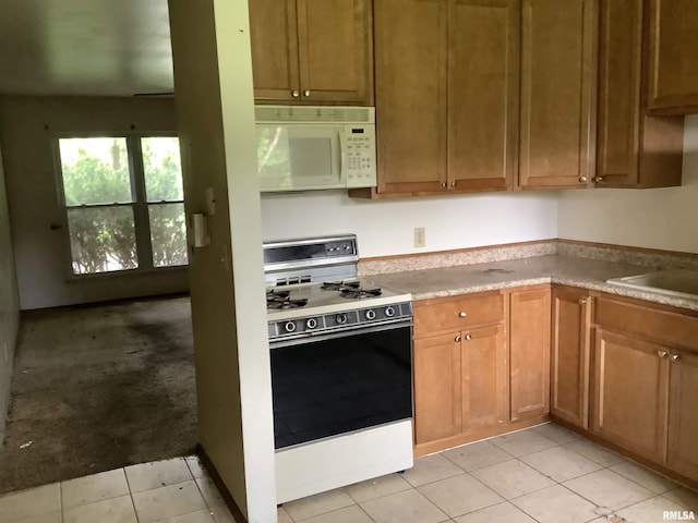 1908 N Idaho St, Peoria, IL 61604 - kitchen with white microwave, electric range, light tile patterned floors, light countertops, and a sink