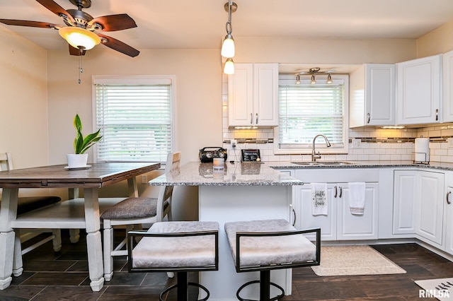 1202 W Purtscher Dr, Peoria, IL 61614 - kitchen with a sink, white cabinetry, backsplash, and light stone countertops