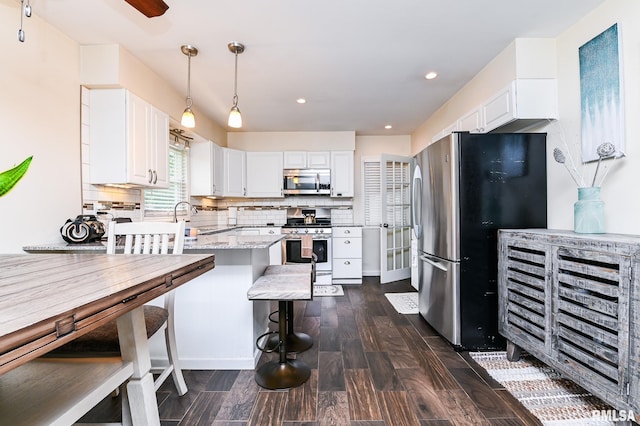 1202 W Purtscher Dr, Peoria, IL 61614 - kitchen featuring stainless steel appliances, dark wood finished floors, white cabinetry, decorative backsplash, and recessed lighting