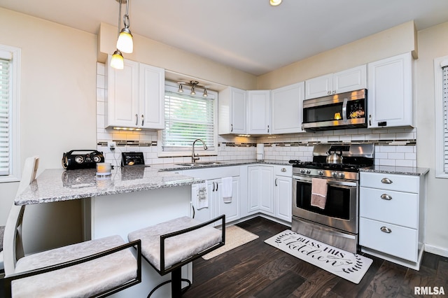 1202 W Purtscher Dr, Peoria, IL 61614 - kitchen featuring stainless steel appliances, a sink, white cabinets, and light stone counters