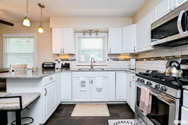 1202 W Purtscher Dr, Peoria, IL 61614 - kitchen featuring appliances with stainless steel finishes, a sink, a peninsula, a kitchen breakfast bar, and white cabinetry
