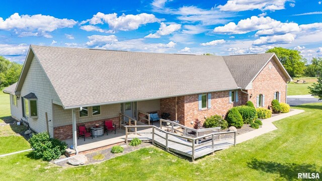 26620 Schuck Rd, Washington, IL 61571 - rear view of house with a lawn, a shingled roof, brick siding, a wooden deck, and a patio area