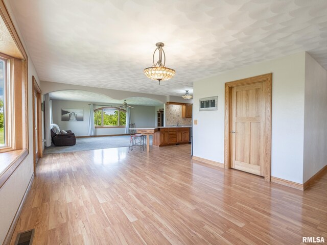 26620 Schuck Rd, Washington, IL 61571 - unfurnished living room featuring arched walkways, light wood-style flooring, baseboards, and a sink
