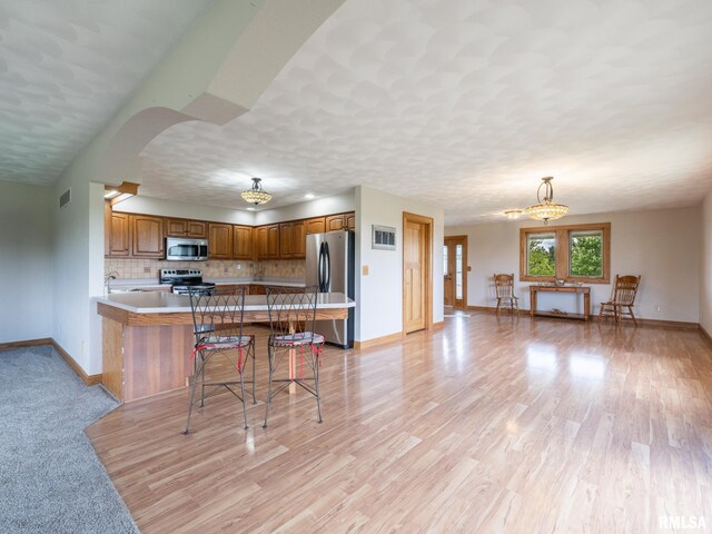 26620 Schuck Rd, Washington, IL 61571 - kitchen featuring appliances with stainless steel finishes, brown cabinetry, baseboards, tasteful backsplash, and a kitchen breakfast bar