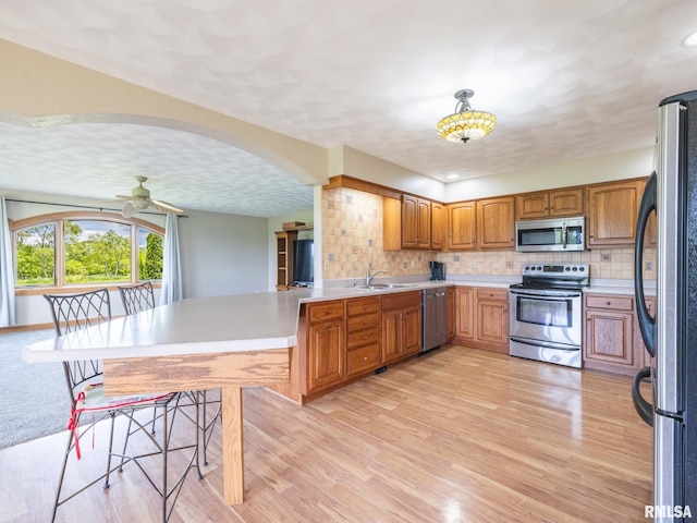 26620 Schuck Rd, Washington, IL 61571 - kitchen featuring appliances with stainless steel finishes, a sink, a peninsula, ceiling fan, and decorative backsplash
