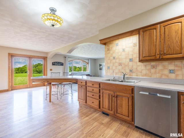 26620 Schuck Rd, Washington, IL 61571 - kitchen with a sink, stainless steel dishwasher, arched walkways, light wood-style floors, and brown cabinetry