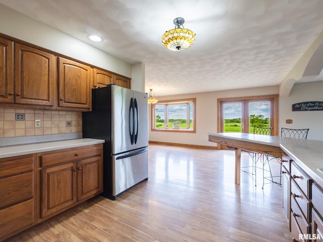 26620 Schuck Rd, Washington, IL 61571 - kitchen with freestanding refrigerator, brown cabinetry, light countertops, and light wood-type flooring