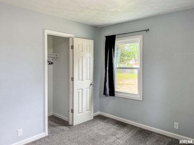 311 N 5th St, Chillicothe, IL 61523 - unfurnished bedroom featuring a walk in closet, carpet flooring, baseboards, and a closet