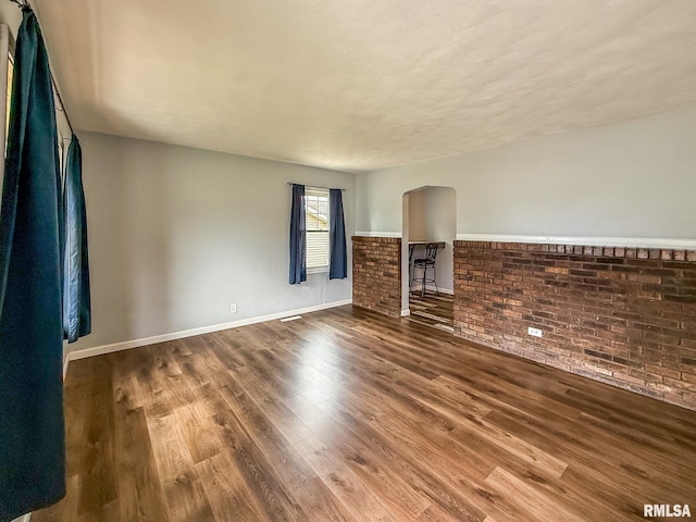 311 N 5th St, Chillicothe, IL 61523 - unfurnished living room with wood finished floors, brick wall, and baseboards