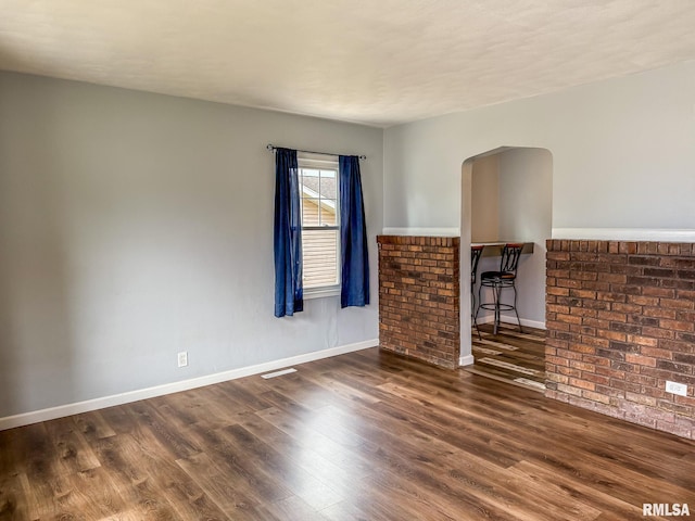 311 N 5th St, Chillicothe, IL 61523 - unfurnished living room featuring wood finished floors, arched walkways, and baseboards