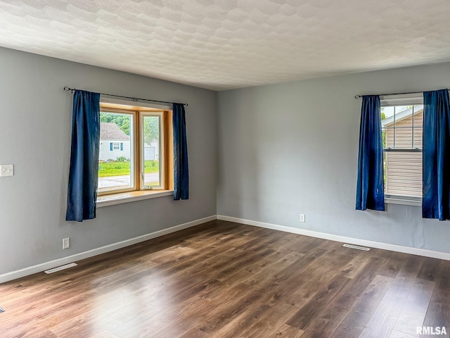 311 N 5th St, Chillicothe, IL 61523 - empty room with plenty of natural light, dark wood-style flooring, baseboards, and a textured ceiling