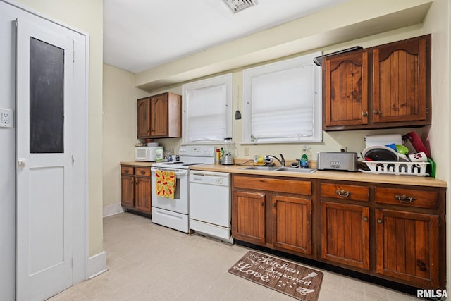 1006 N Maplewood Ave, Peoria, IL 61606 - kitchen with a sink, white appliances, light countertops, baseboards, and brown cabinetry