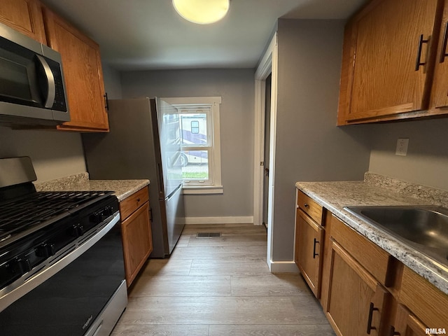 210 Minch St, South Pekin, IL 61564 - kitchen with appliances with stainless steel finishes, brown cabinets, light wood-style flooring, light countertops, and baseboards