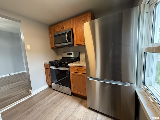 210 Minch St, South Pekin, IL 61564 - kitchen featuring appliances with stainless steel finishes, light wood-type flooring, brown cabinetry, and baseboards