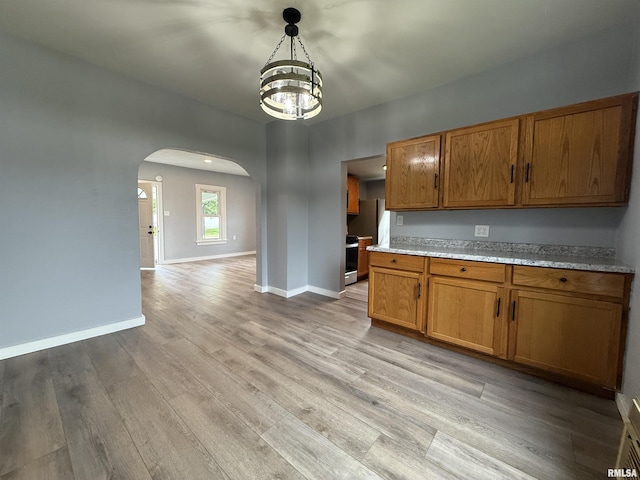 210 Minch St, South Pekin, IL 61564 - kitchen featuring arched walkways, a chandelier, brown cabinets, light wood-style floors, and baseboards