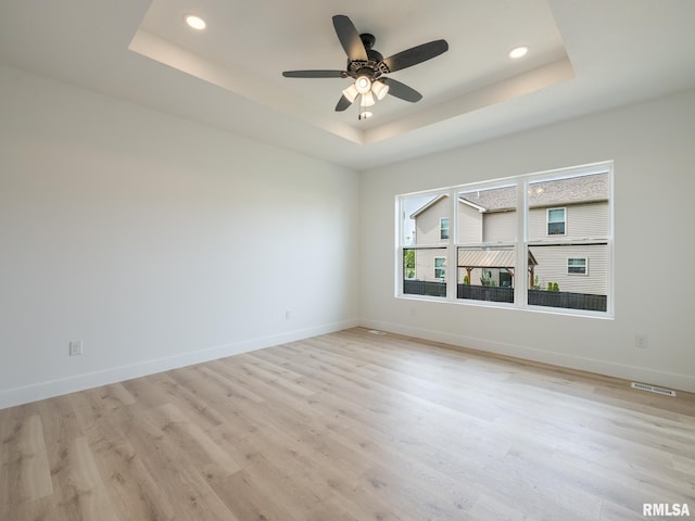 112 Shannon Hills Dr, Washington, IL 61571 - spare room with a tray ceiling, light wood finished floors, a ceiling fan, recessed lighting, and baseboards