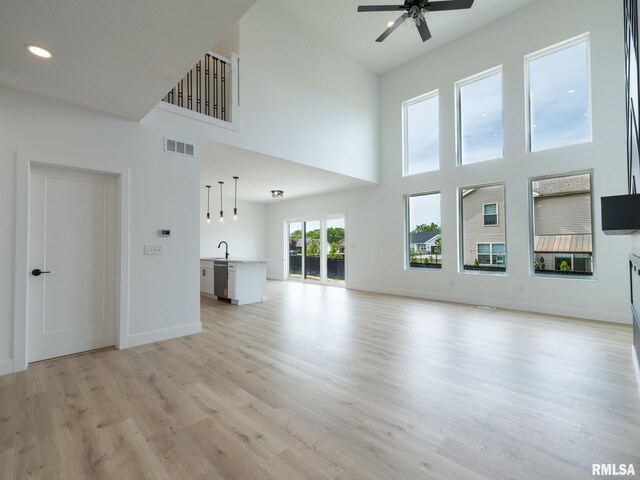 112 Shannon Hills Dr, Washington, IL 61571 - unfurnished living room featuring a towering ceiling, a ceiling fan, light wood-style flooring, a sink, and baseboards