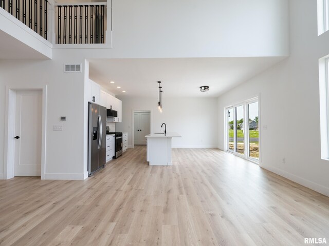 112 Shannon Hills Dr, Washington, IL 61571 - unfurnished living room featuring a towering ceiling, light wood-style floors, baseboards, a sink, and recessed lighting