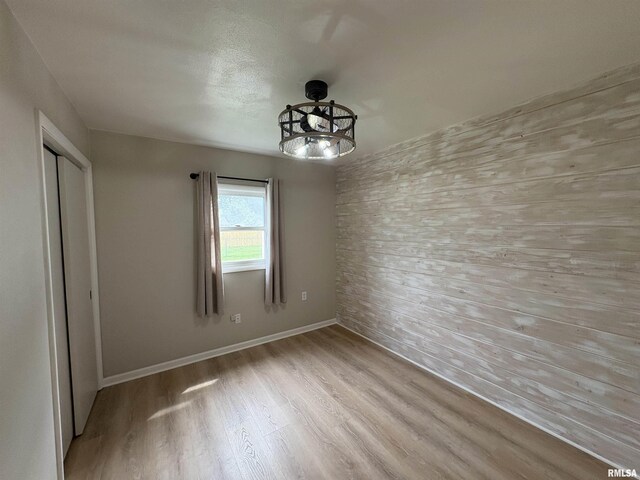 606 Lasalle Blvd, Marquette Heights, IL 61554 - unfurnished bedroom with wood finished floors, wooden walls, a closet, and baseboards