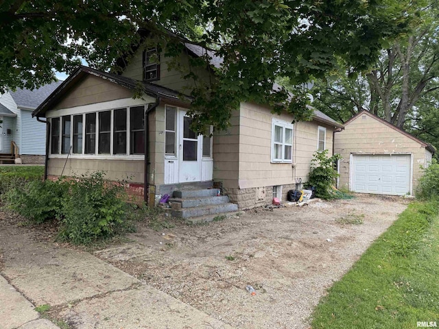 405 Hamilton St, Washington, IL 61571 - bungalow-style home featuring a sunroom, an outbuilding, dirt driveway, a garage, and entry steps