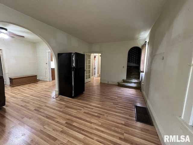 102 W 1st St, Table Grove, IL 61482 - unfurnished living room with arched walkways, light wood finished floors, ceiling fan, and baseboards